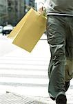 Jeune homme qui marche avec sac à provisions