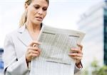 Businesswoman reading financial pages of newspaper