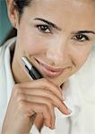 Businesswoman holding pen, smiling, portrait