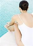 Woman sitting by edge of pool