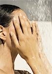 Woman touching face under shower, close-up