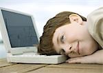 Boy resting head on laptop