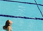 Femme debout dans la piscine avec la tête en arrière et les yeux fermés