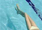 Woman floating in pool, view from waist down