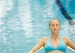 Femme relaxante au bord de piscine, les yeux fermés