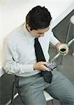 Executive holding cup of coffee and checking cell phone