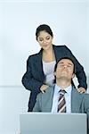 Woman massaging businessman's shoulders
