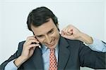 Businessman using cell phone, smiling, and making fist