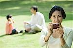 Woman aiming digital camera, smiling at camera