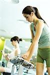 Woman picking up dumbbells in health club