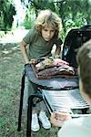 Two boys standing at either end of barbecue