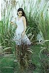 Woman standing among long grasses and reeds, full length