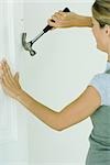 Woman removing nail from wall