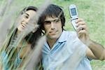 Young couple taking photos of selves with cell phone