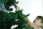 Girl touching branch of Christmas tree