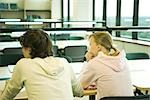 Deux étudiants assis à table en bibliothèque, vue arrière