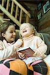 Girl and toddler sitting on couch, laughing