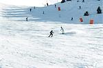 Jeunes skieurs sur la piste de ski, au loin