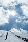 Young skiers using ski lift on hill. rear view, in the distance