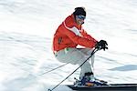 Reifen männlichen Skifahrer auf der Piste, lächelnd in Richtung Kamera, Bewegungsunschärfe