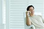 Man using cell phone on porch, smiling
