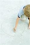 Child drawing circle in the sand with a stick, cropped view