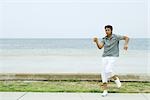 Man listening to headphones and dancing at the beach, full length