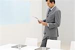 Business executive standing in office, reading report