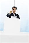 Executive standing behind lectern, pointing with pen at camera