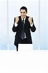Businessman standing with fists up, smiling at camera