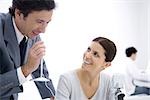 Businessman holding microphone while female colleague watches