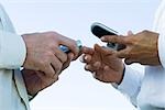 Two men face to face, holding cell phones, cropped view of hands