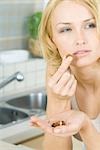 Woman eating a nut, several more in her hand