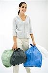 Teen girl carrying several garbage bags, smiling at camera