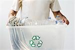 Man carrying recycling bin filled with plastic bottles and newspaper, cropped