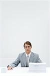 Businessman sitting at table with two different sized stacks of paper