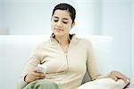 Junge Frau sitzt auf dem Sofa, MP3-Player anhören