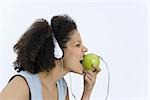 Femme portant des écouteurs branchés sur apple, mordre dans la pomme, profil