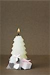 White Christmas tree shaped candle with miniature gifts set at base