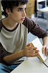 Male high school student in class, holding book