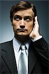 Businessman with hand cupped around ear listening attentively