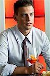 Young man in business suit sitting with glass of orange wine