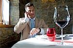 Young man in suit with mobile phone at a restaurant checking time