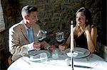 Couple sitting at restaurant table toasting with red wine