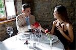 Young man giving a present to young woman at restaurant table