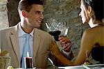 Couple sitting at restaurant table toasting with red wine