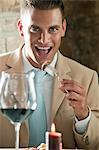 Jeune homme manger avec verre de vin dans un restaurant