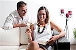 Young man leaning on couch with young woman with book and white wine