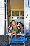 Boy sitting in door of camper with dogs