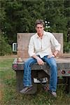 Young Man Sitting on end of Flatbed Truck near Brush Prairie, Washington, USA